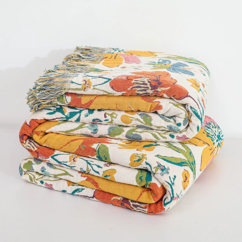 Wendbare Sofadecke aus Baumwollgaze mit Quasten und leuchtendem Blumenmuster