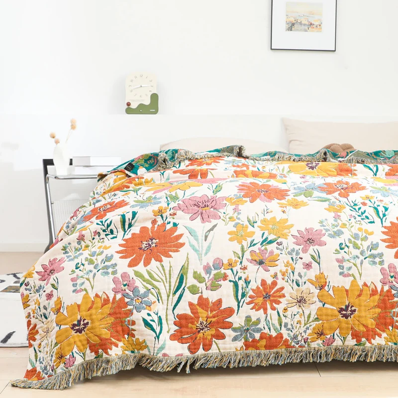 Wendbare Sofadecke aus Baumwollgaze mit Quasten und leuchtendem Blumenmuster